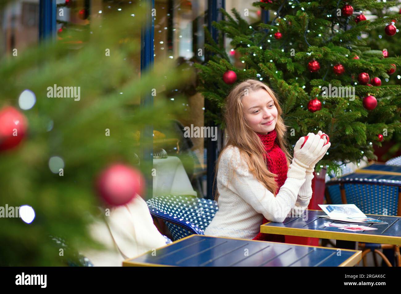 Girl writing Christmas postcards in an outdoor Parisian cafe Stock Photo