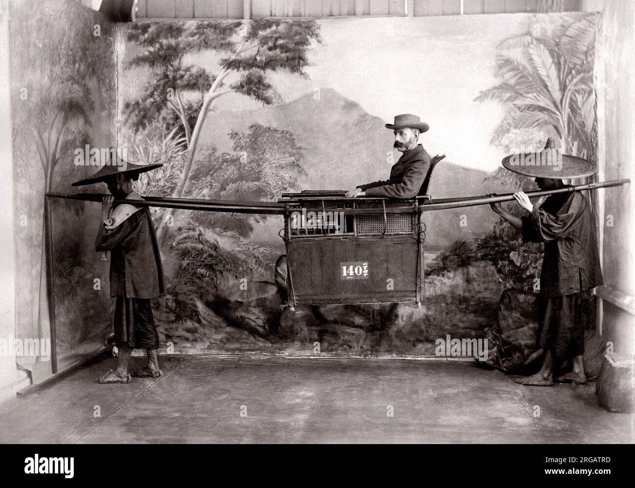 c.1880s China - man in a sedan chair with bearers, studio setting, palanquin Stock Photo