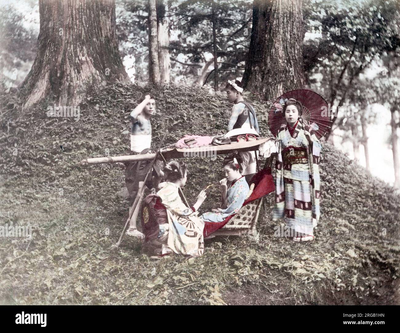 c. 1880s Japan - geishas with carrying chair and bearers in a wood Stock Photo