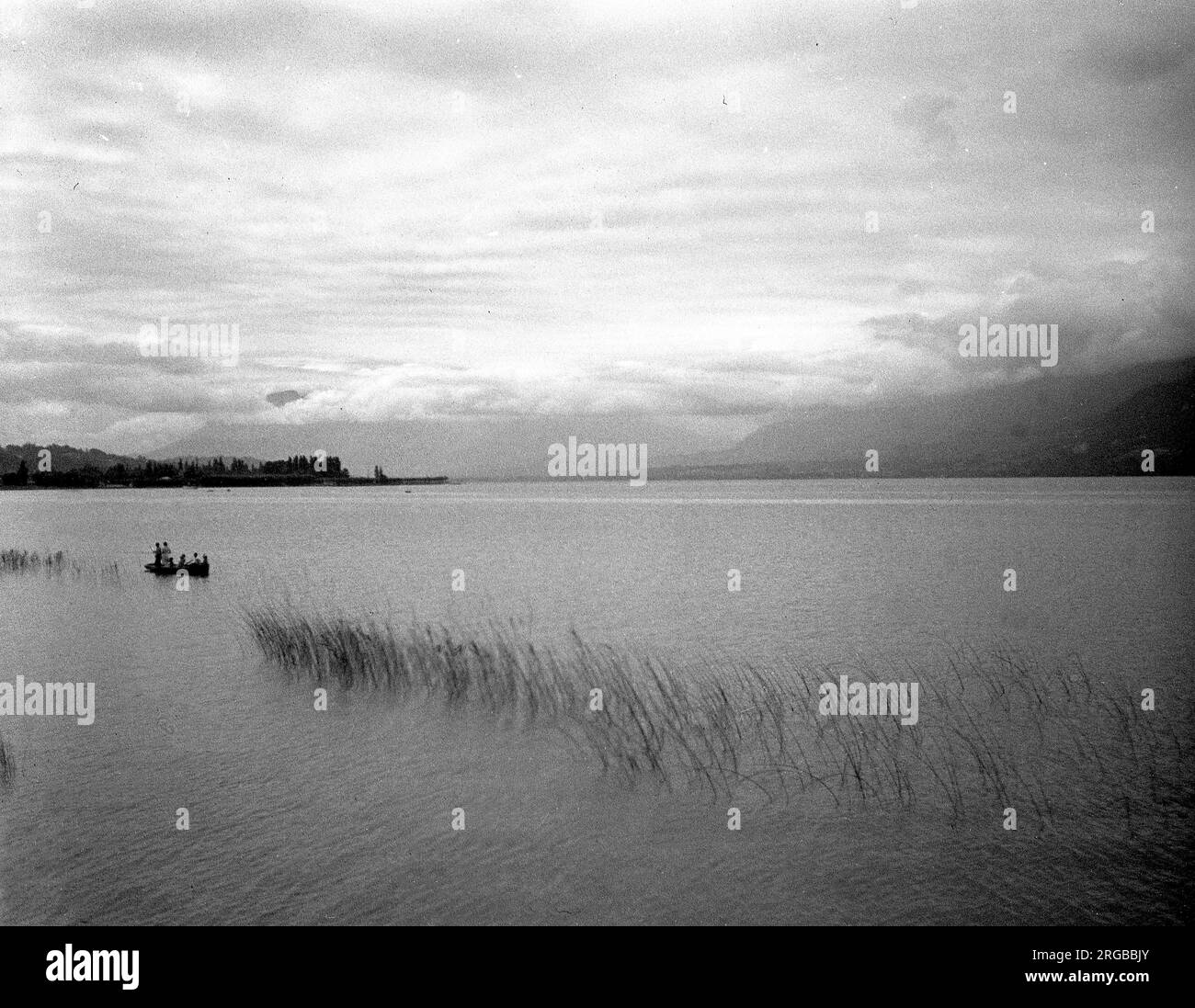Unknown French mountain lake, with a family fishing from a boat. Stock Photo