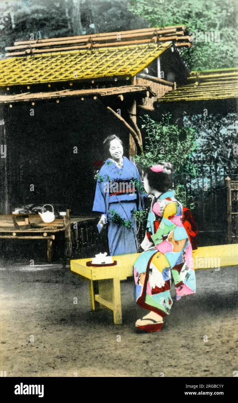 Two Japanese women in traditional costume taking tea in a garden. Stock Photo