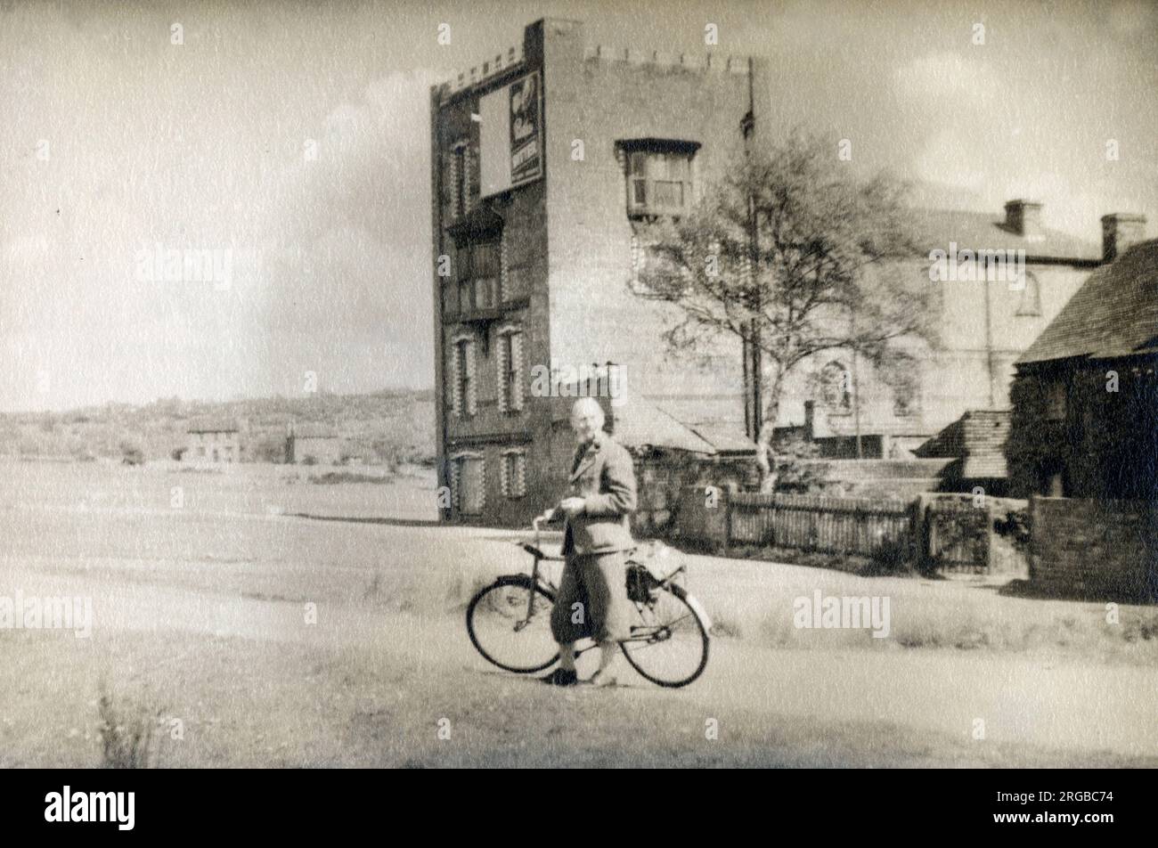 A smart gentleman out for a cycle (in his plus-fours) pauses in front of an unusual building, which appears to be part-castle, part-church and part-townhouse - location sadly unidentified... Stock Photo