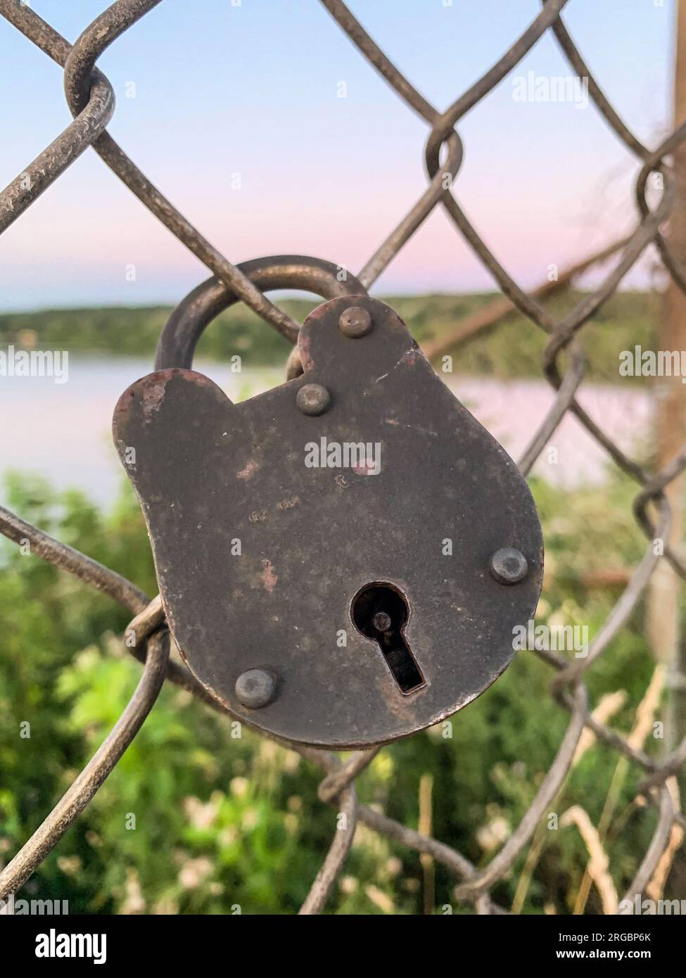 Old lock hanging on wire mesh Stock Photo