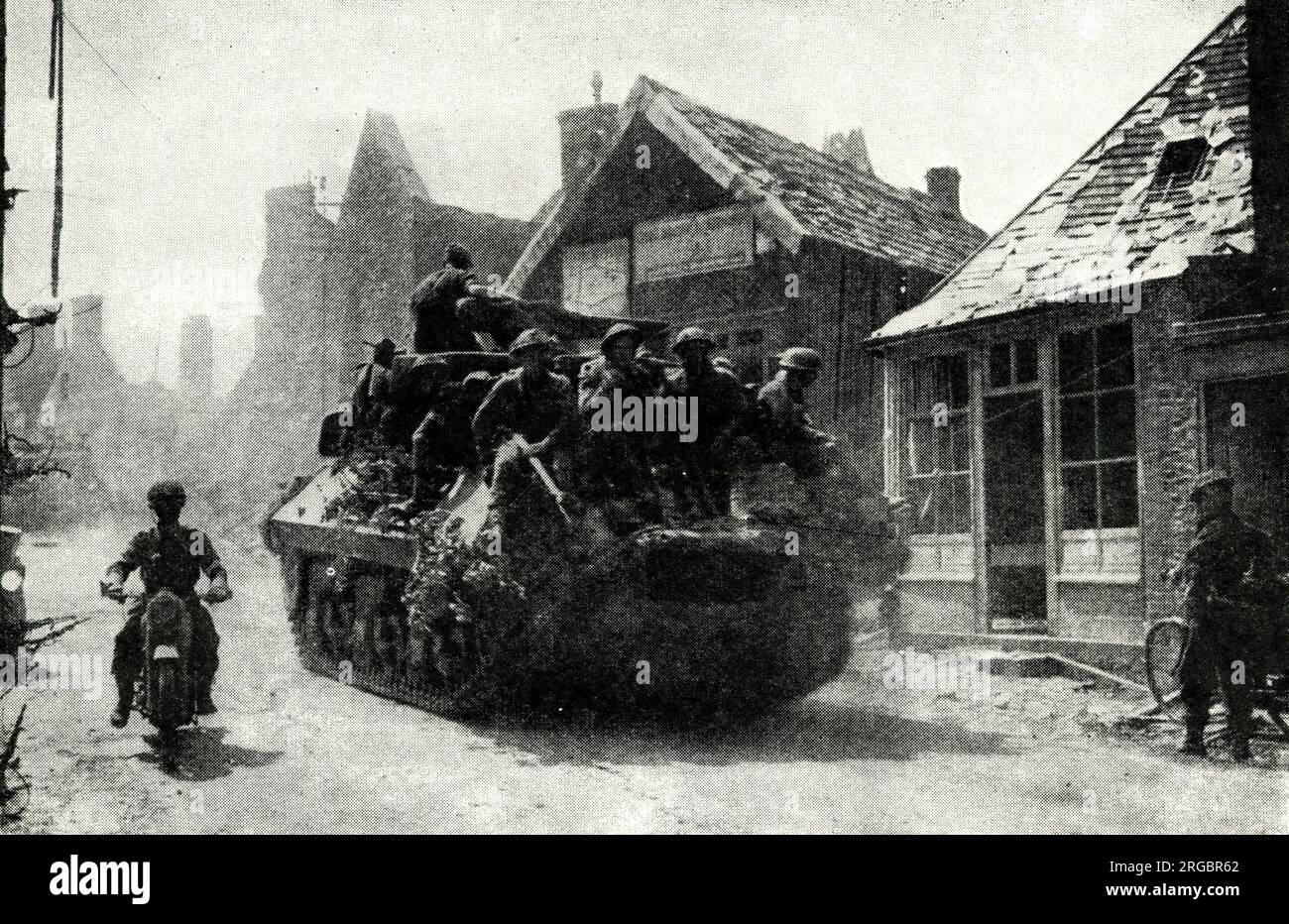 Allied forces cross frontier into Belgium, 2 September 1944, WW2 - a tank loaded with soldiers passes through a town. Stock Photo
