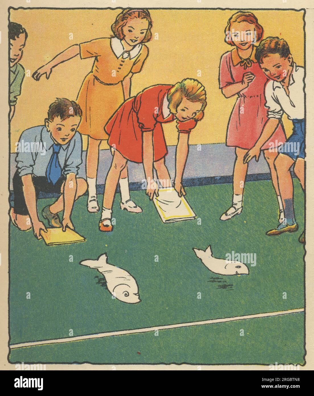 Children playing a game of Flap the Kipper. Cut two fish shapes out of thin paper and lay them parallel. Then two children, each armed with an exercise book, flap hard behind the fishes (but never touching them) to see who can be the first to blow their fish over the line. Stock Photo