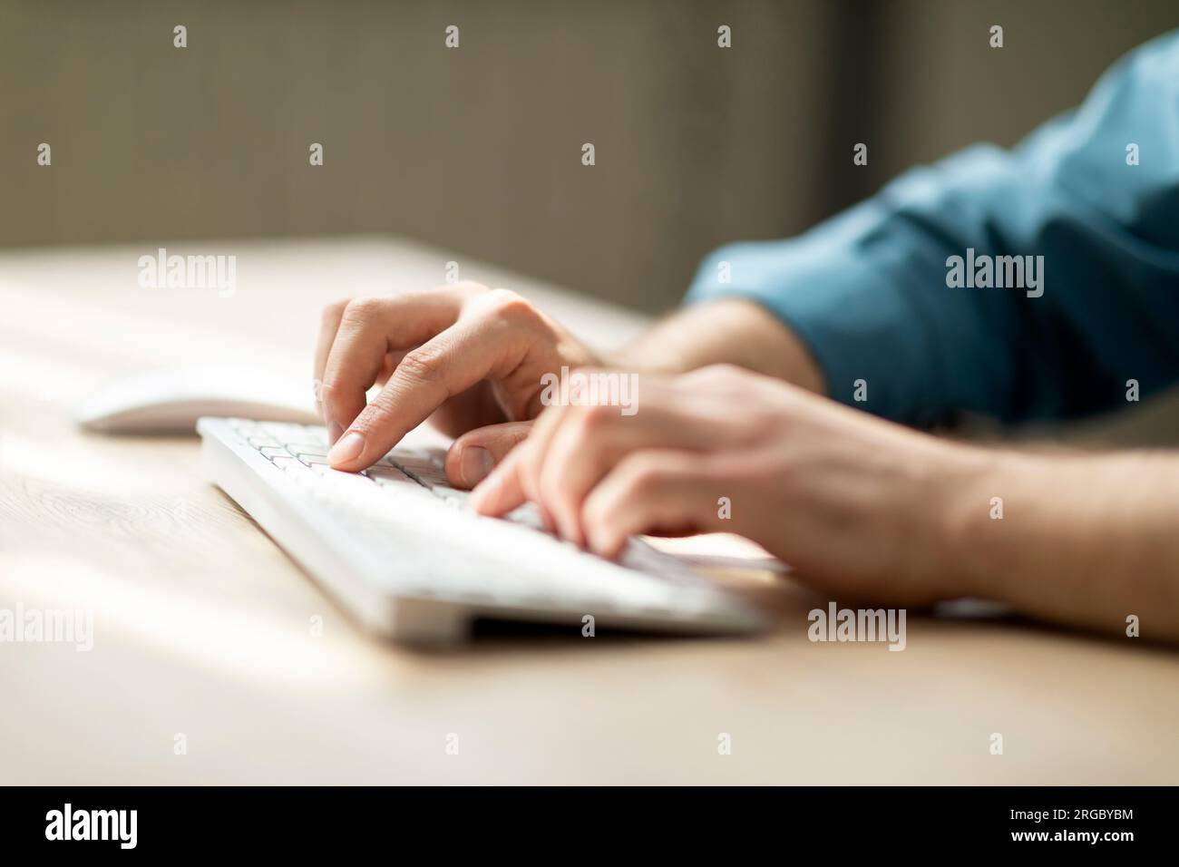 Unrecognizable man typing on computer keyboard while sitting at desk Stock Photo