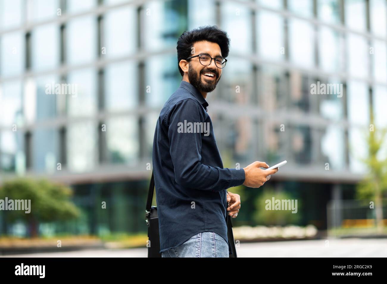 Happy middle eastern IT professional going to office, using phone Stock Photo