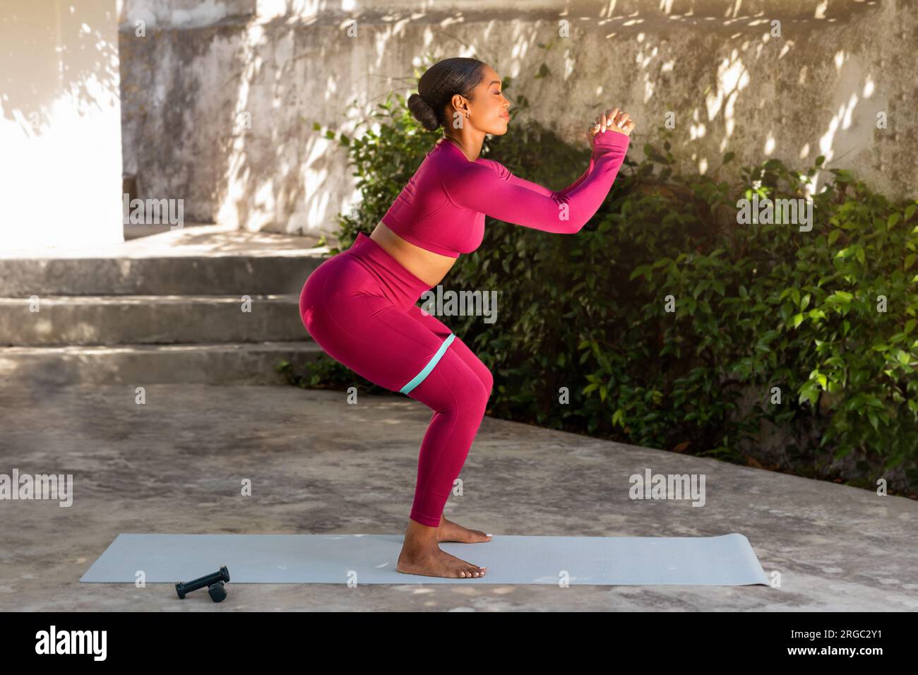 Sporty young black woman exercising on yoga mat at garden Stock Photo ...