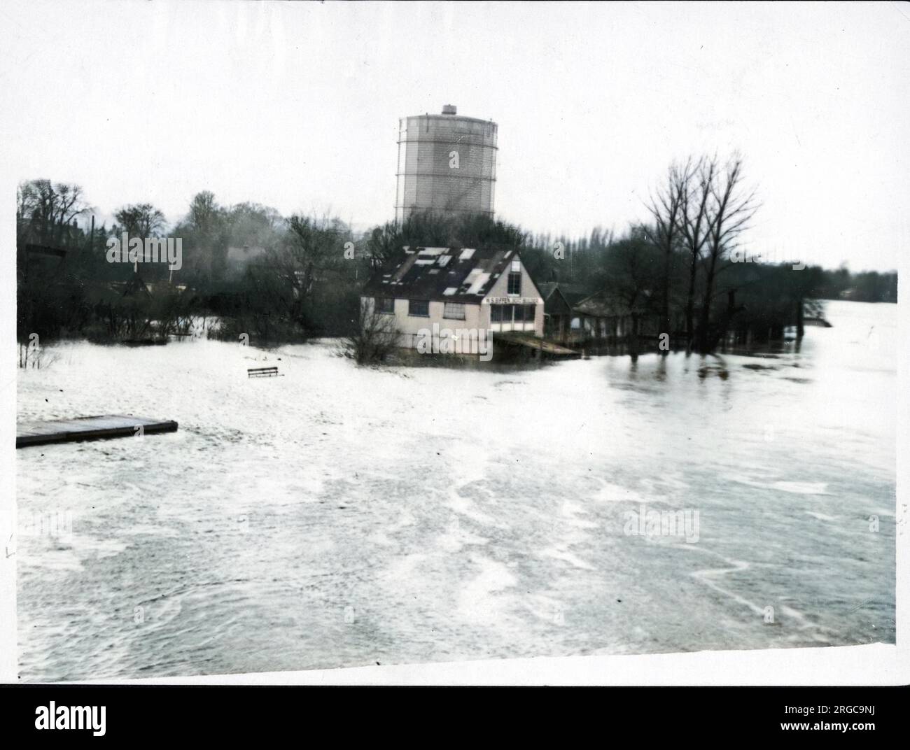Flood water from the river Thames at Staines in Surrey, threatens the premises of W S Biffen Boat Builder and the gasometer, one of the largest in the world Stock Photo