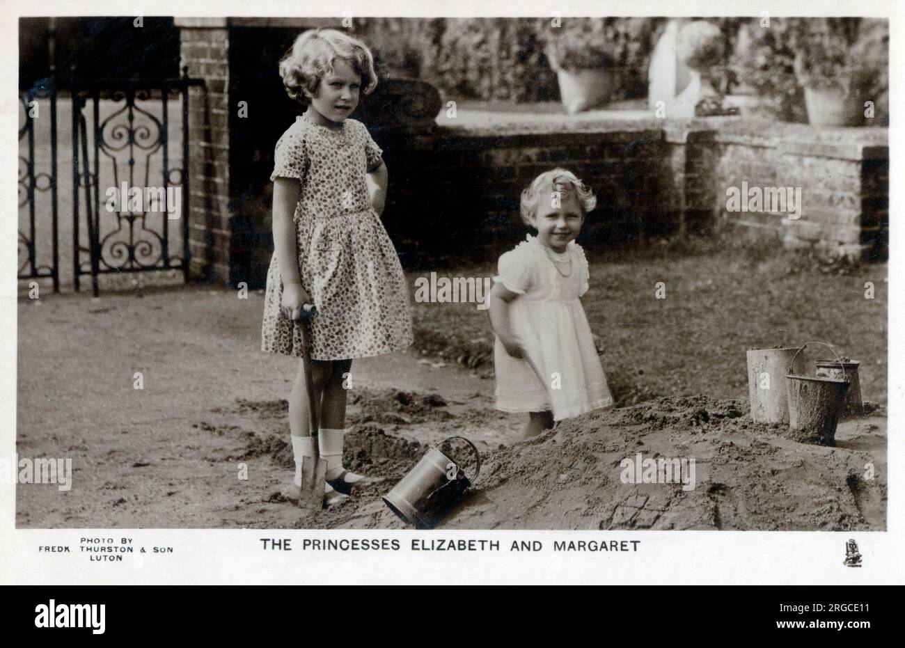 Princesses Elizabeth (later Queen Elizabeth II) (1926-) and Margaret (1930-2002), daughters of the Duke and Duchess of York playing in a sandpit at St. Paul's Walden Bury, Welwyn, Herts - the residence of their Grandparents the Earl and Countess of Strathmore. Stock Photo