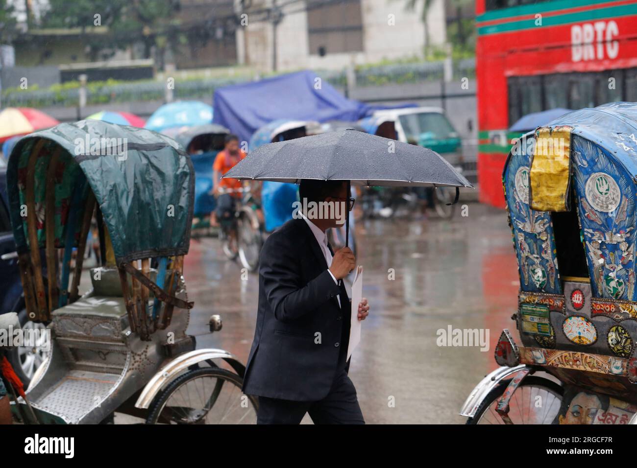DHAKA, BANGLADESH AUGUST 8, 2023 A man holds an umbrella during