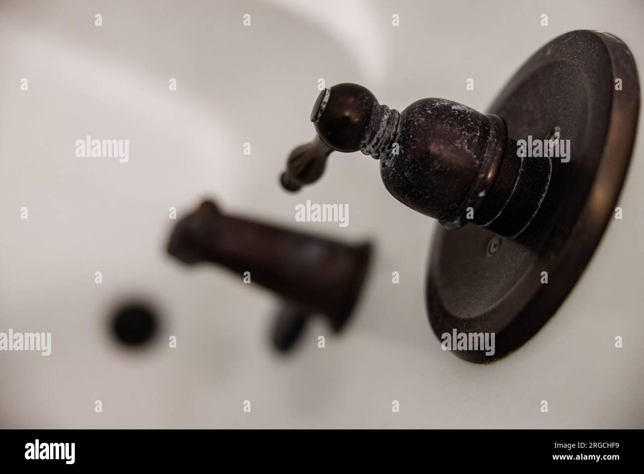 An oil rubbed bronze shower handle that needs to be cleaned from a