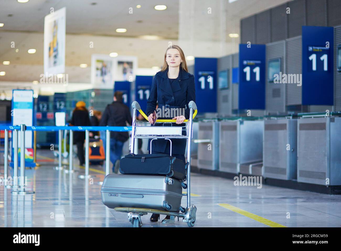 Young woman in international airport, with luggage trolley Stock Photo ...