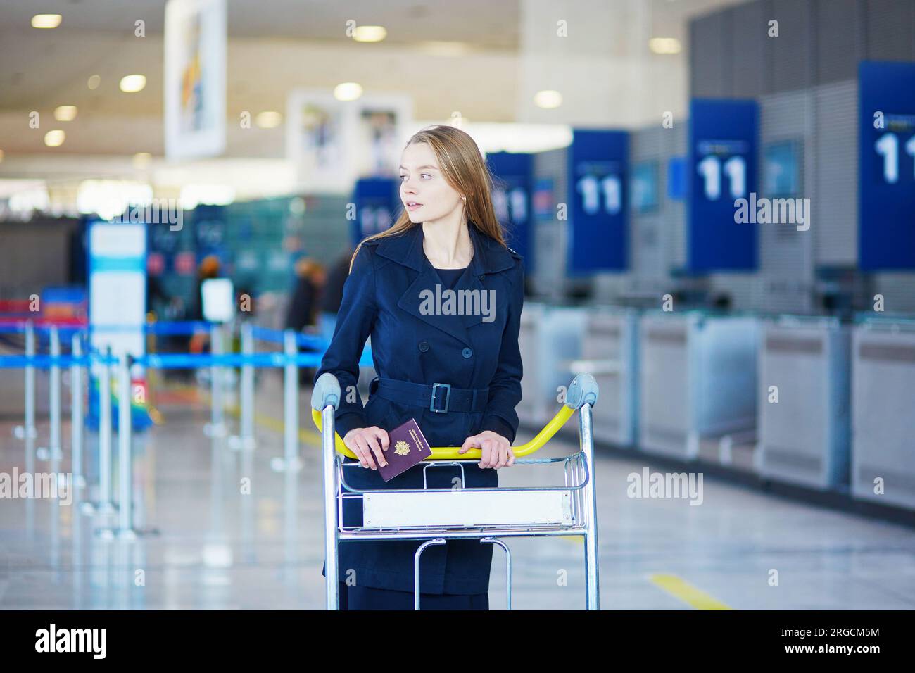 Young woman in international airport, with luggage trolley Stock Photo ...