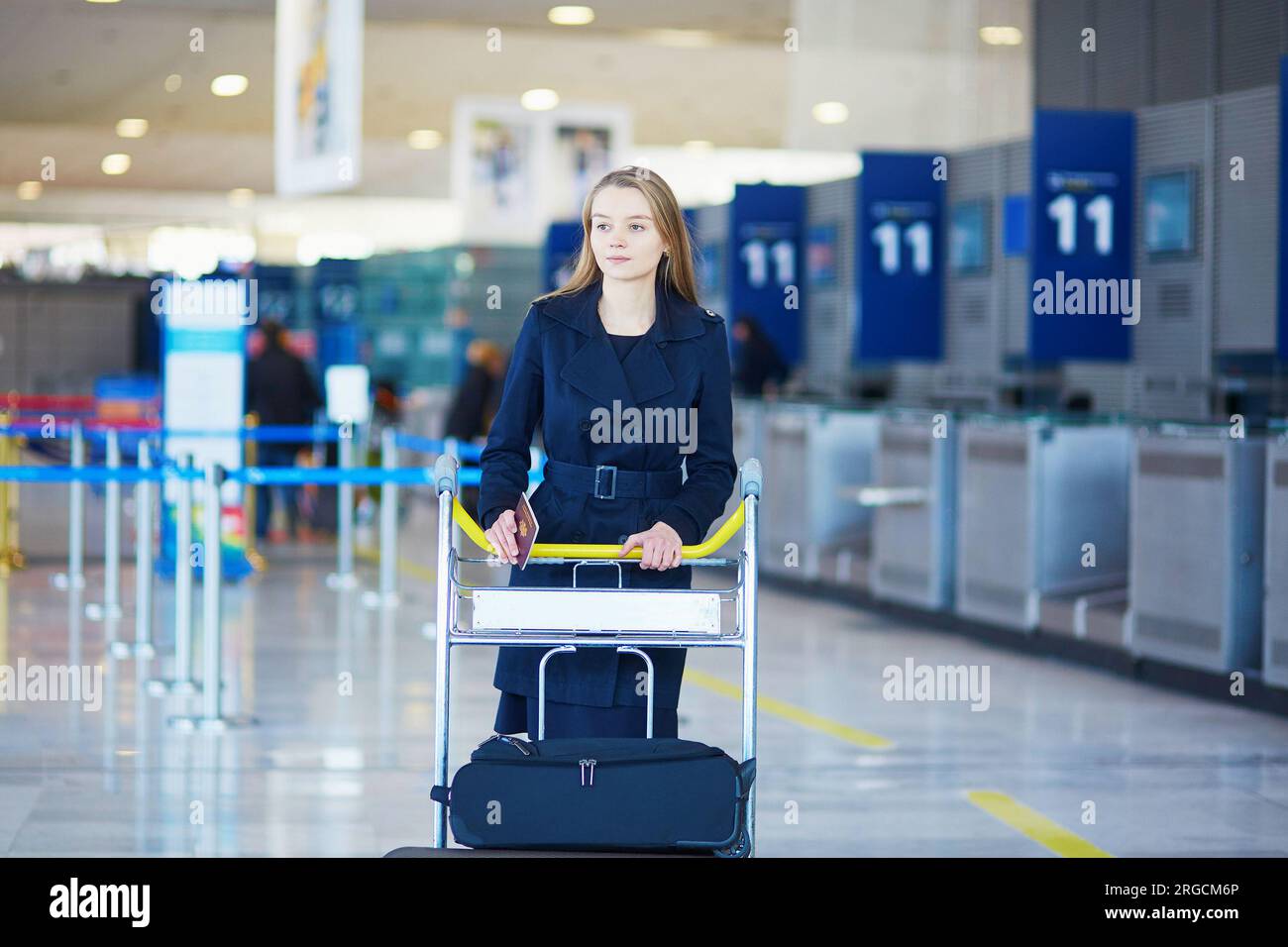 Young woman in international airport, with luggage trolley Stock Photo ...
