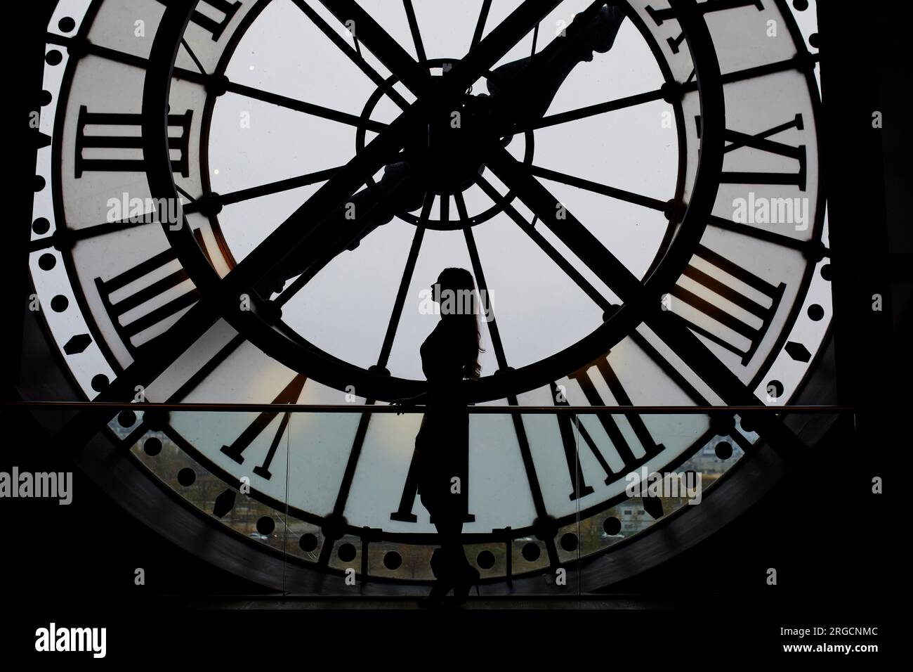 Woman silhouette standing in front of large clock paris france