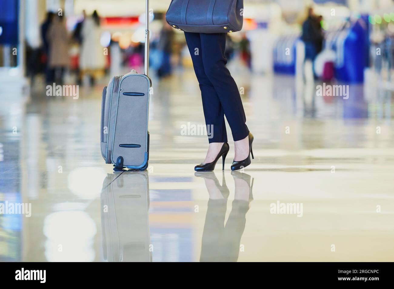 Elegant business woman with hand luggage in international airport terminal. Cabin crew member with suitcase. Unrecognizable person, closeup of legs Stock Photo