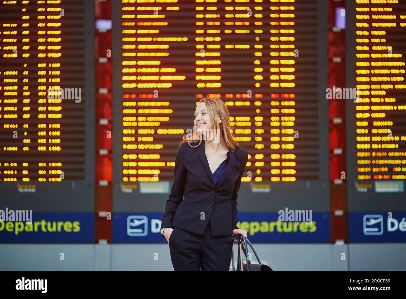 Young elegant business woman with hand luggage in international airport ...