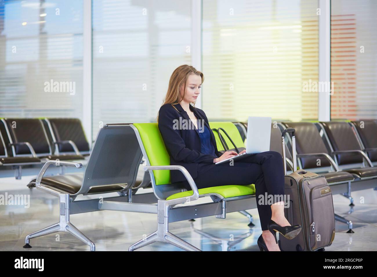 Young elegant business woman with hand luggage in international airport