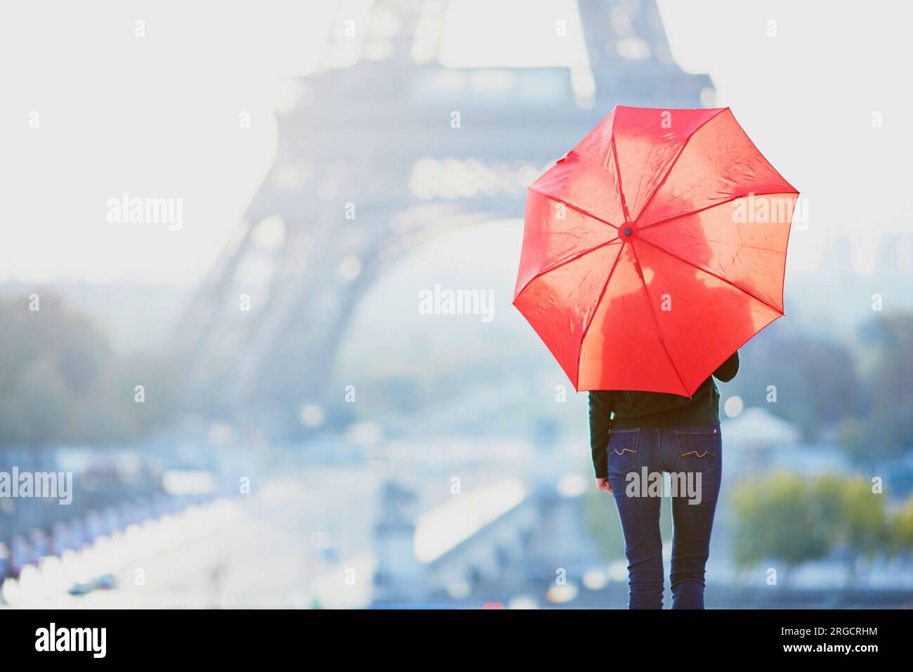 Beautiful young girl with red umbrella in Paris near the Eiffel tower