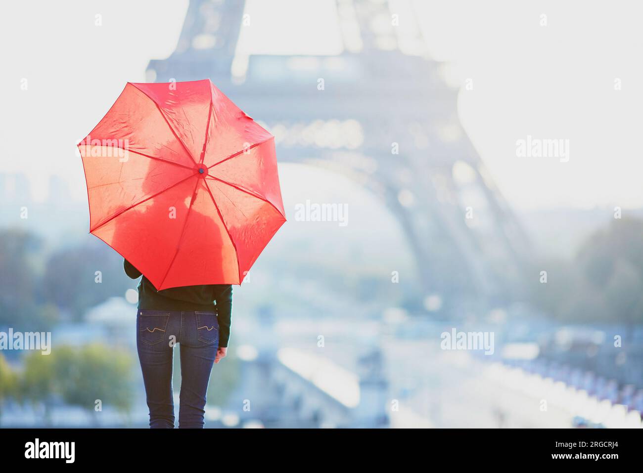 Beautiful young girl with red umbrella in Paris near the Eiffel tower