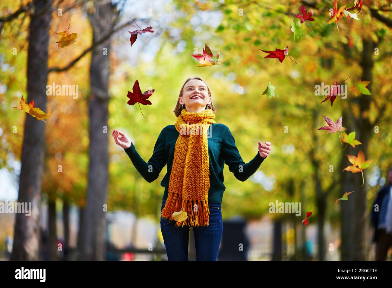 Beautiful young woman with htrowing colorful autumn leaves while ...