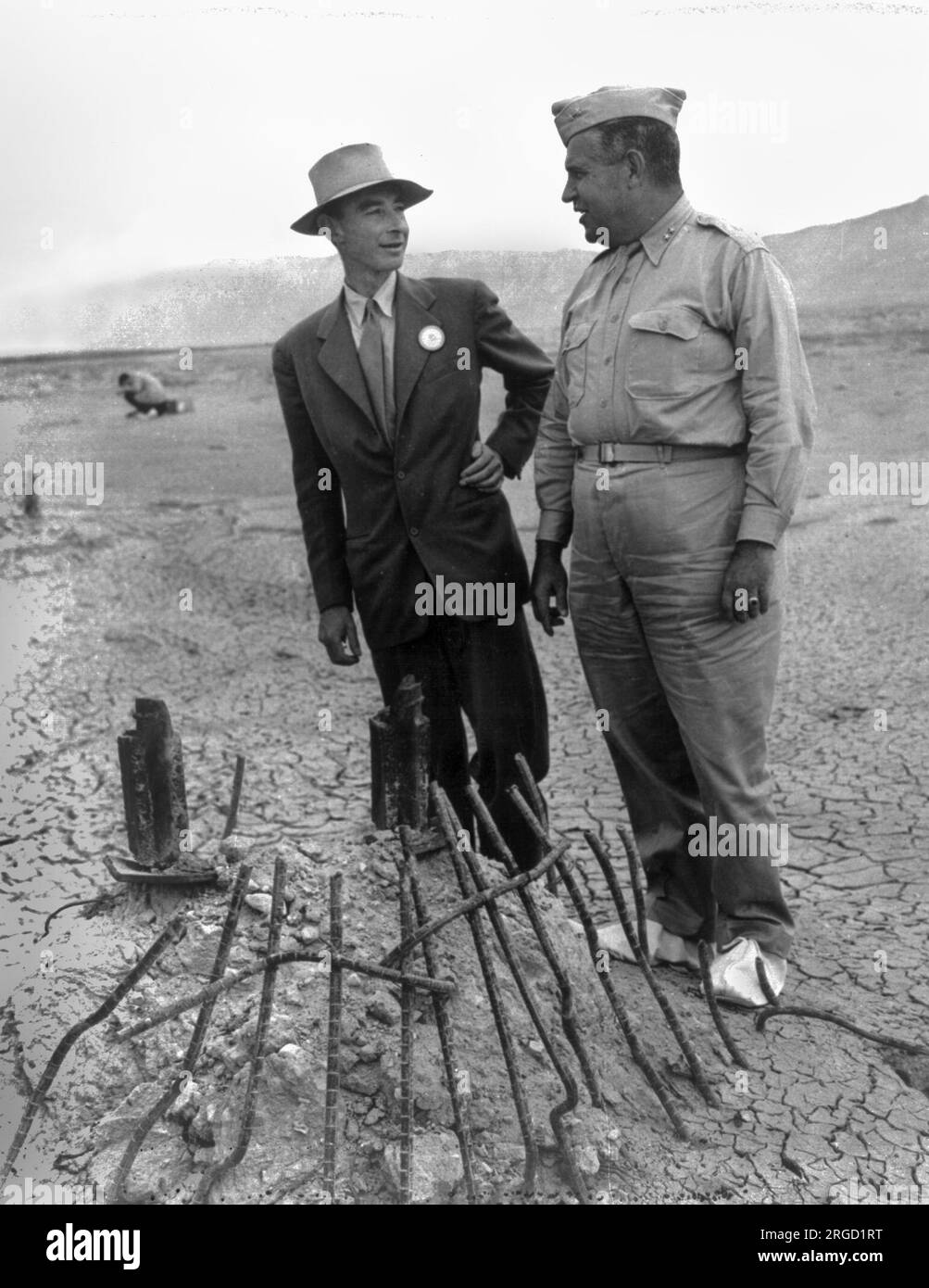 In September 1945, many participants returned to the Trinity Test site for news crews. Here Robert Oppenheimer and General Leslie Groves examine the remains of one the bases of the steel test tower. Stock Photo