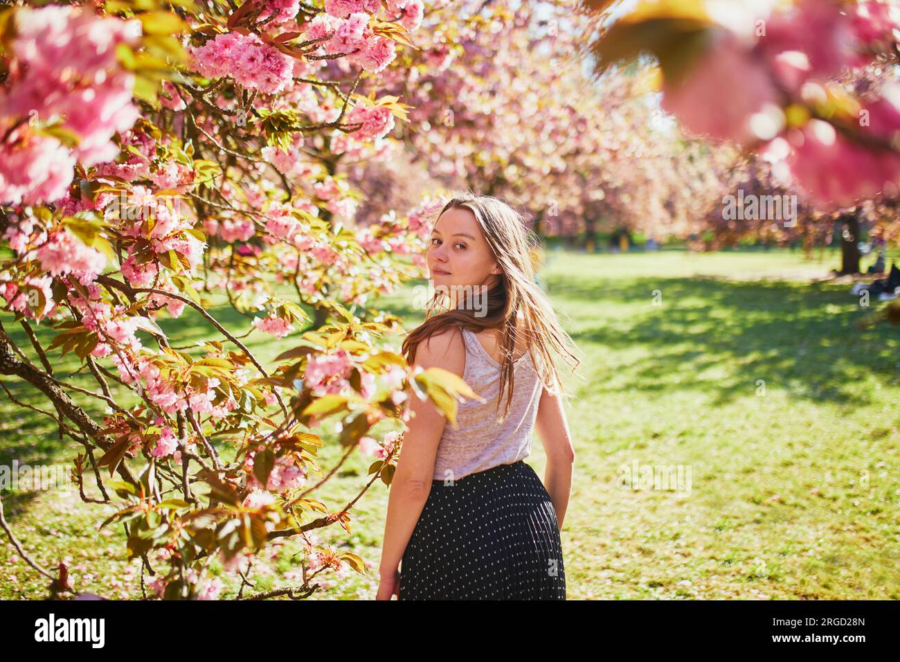 Beautiful girl in cherry blossom garden on a spring day. Young woman in ...