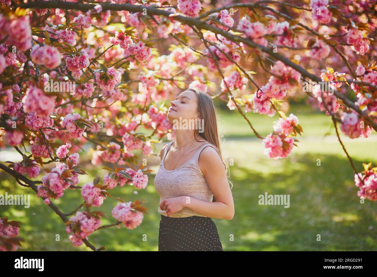 Beautiful girl in cherry blossom garden on a spring day. Young woman in ...