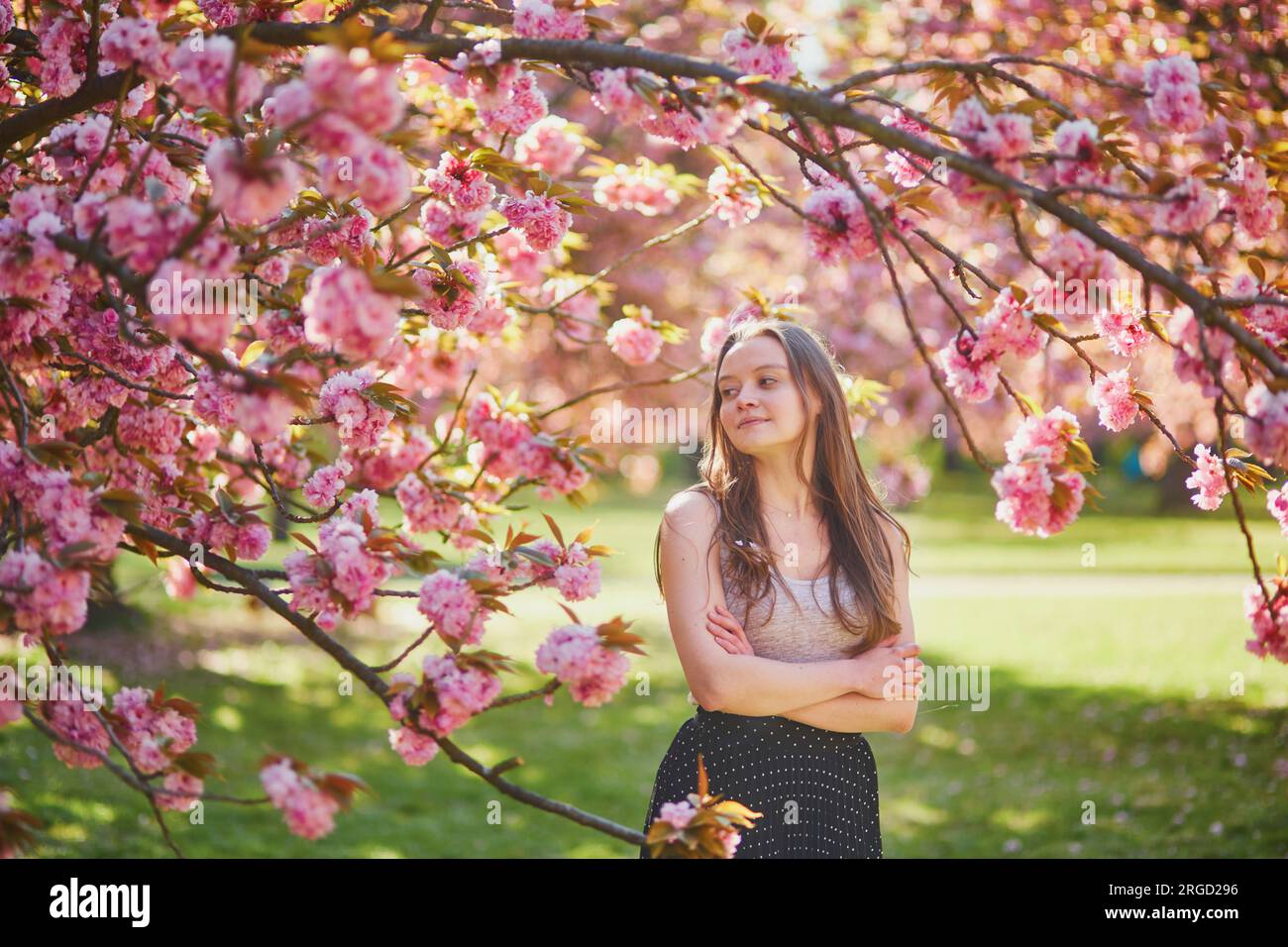 Beautiful girl in cherry blossom garden on a spring day. Young woman in ...