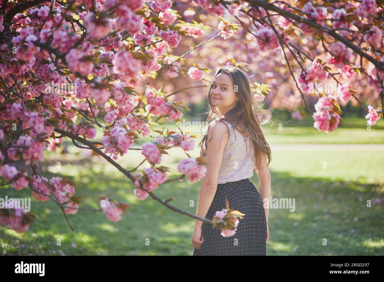 Beautiful girl in cherry blossom garden on a spring day. Young woman in ...