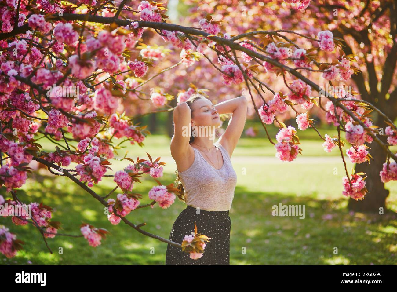 Beautiful girl in cherry blossom garden on a spring day. Young woman in ...