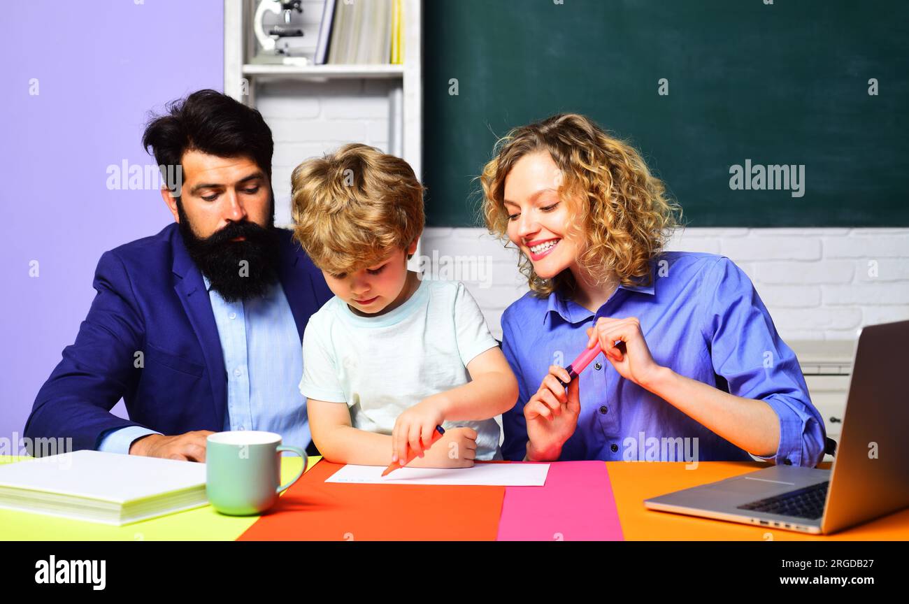 Teachers helping kid from primary school in classroom doing homework. Knowledge, studying and learning. Little child boy student in elementary school Stock Photo