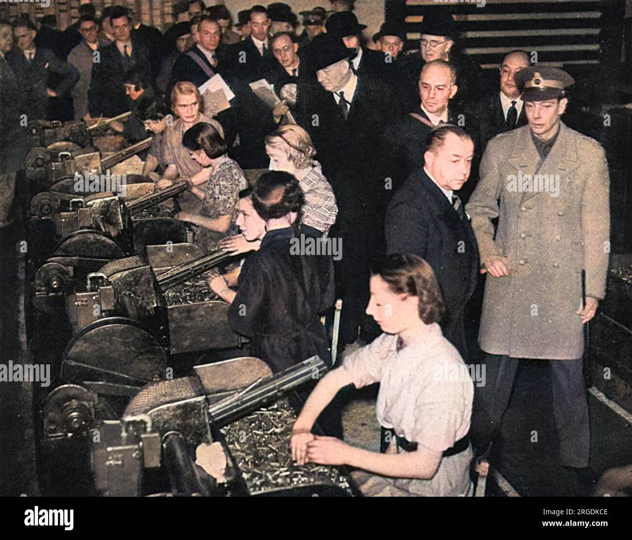 King George VI being given a tour of inspection of a Royal Ordnance factory and seeing at first-hand the immense effort being put in to produce arms, in this case anti-aircraft and anti-tank guns.  Picture shows the King watching some of the women workers in the factory sorting ammunition. Stock Photo