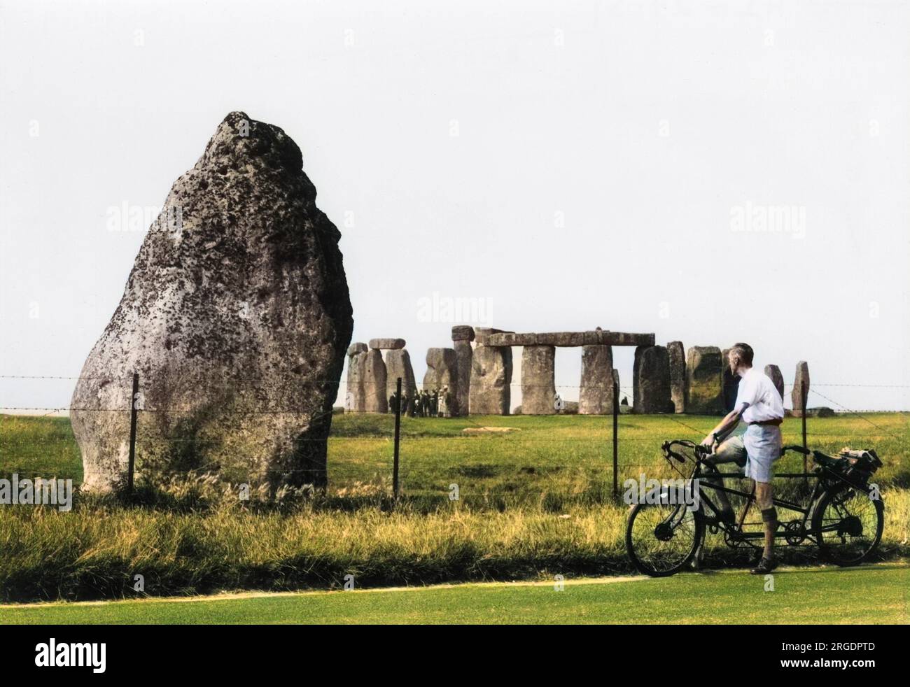 A cyclist on a tandem stops to admire the ancient standing stones at Stonehenge, Wiltshire, England, where a guided tour is taking place. Stock Photo