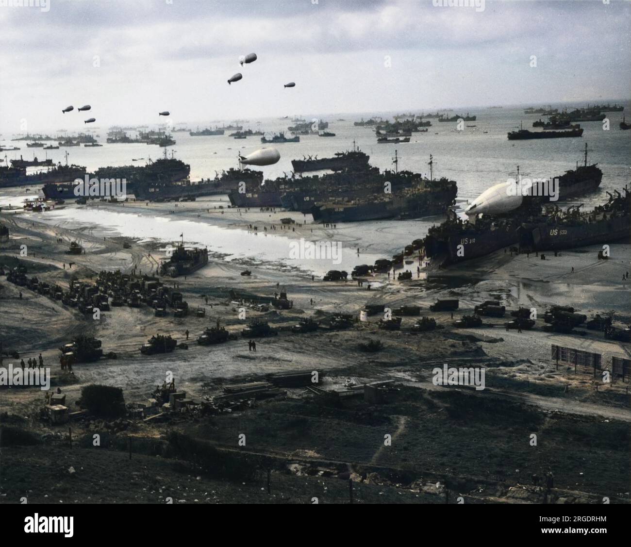 A stunning panorama photograph of a French invasion beach with the channel waters thick with US military shipping, as reinforcements and supplies are funneled ashore following the conquest of the Cherbourg peninsula. Barrage balloons protect the ships from enemy strafing. One balloon still rests on the deck of large landing vehicle. Trucks filled with supplies and troops head inland across the beach. D-Day began on June 6th, 1944 at 6:30am and was conducted in two assault phases û the air assault landing of allied troops followed by an amphibious assault by infantry. The Normandy landings were Stock Photo