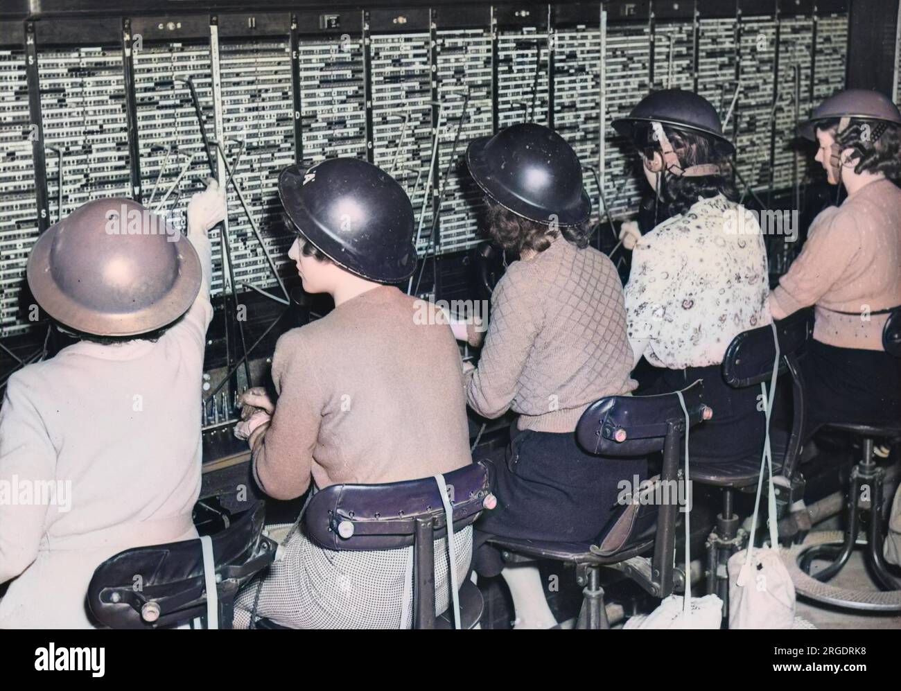 Women telephone operators at a London telephone exchange with tin helmets, during World War II Stock Photo