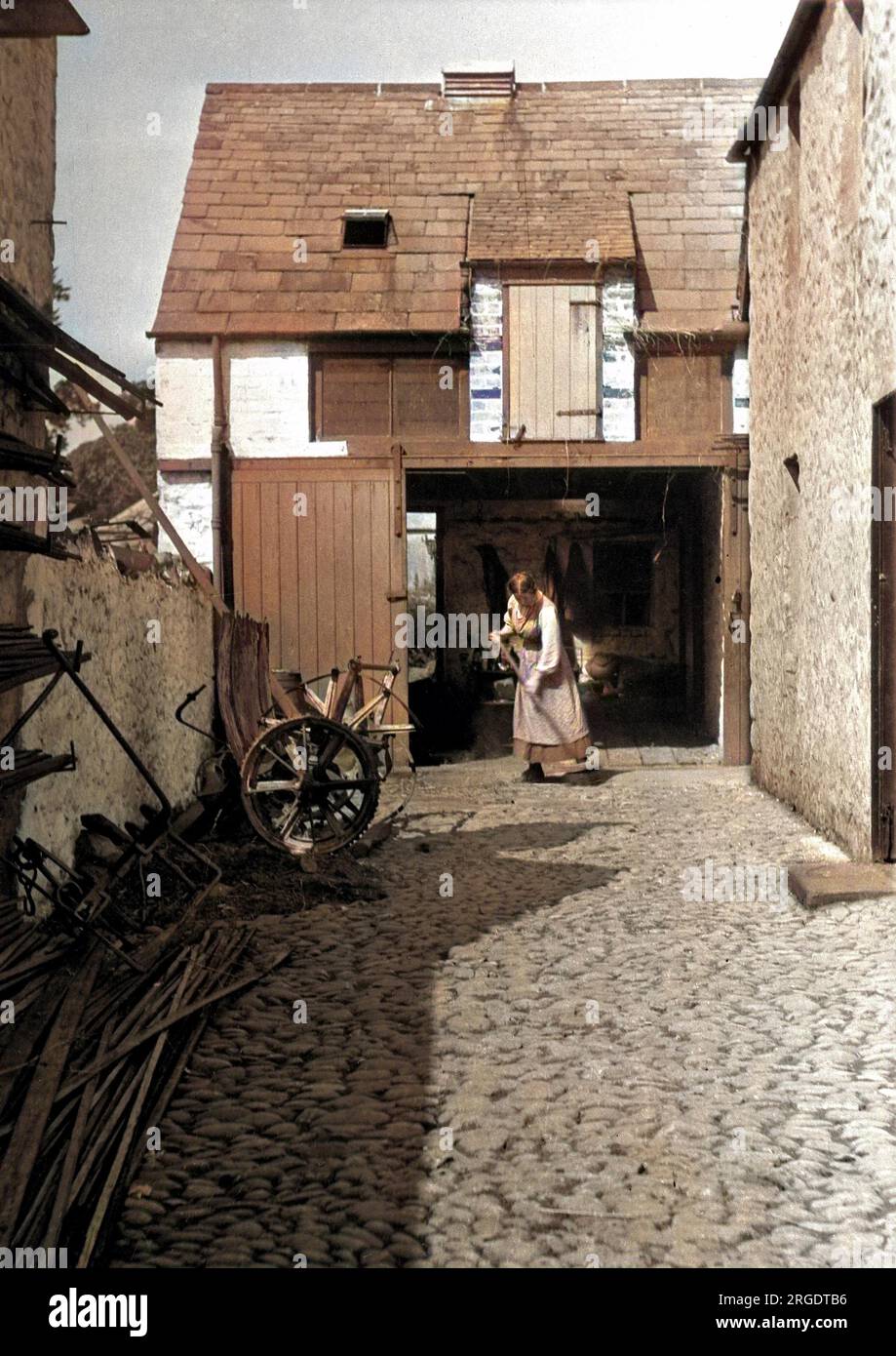 A woman sweeping a yard outside a barn Stock Photo Alamy