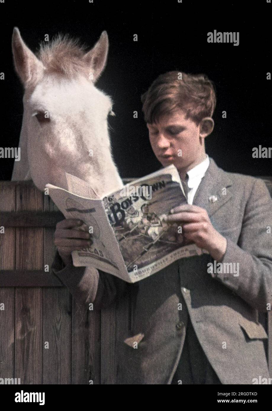 A boy stands reading his Boy's Own magazine, while a white horse appears to be reading over his shoulder. Stock Photo