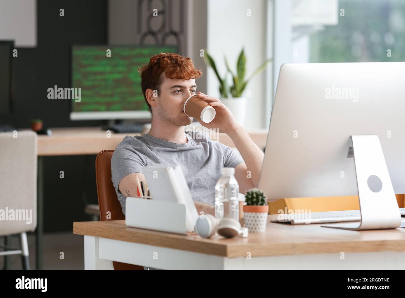 Male programmer drinking coffee at table in office Stock Photo
