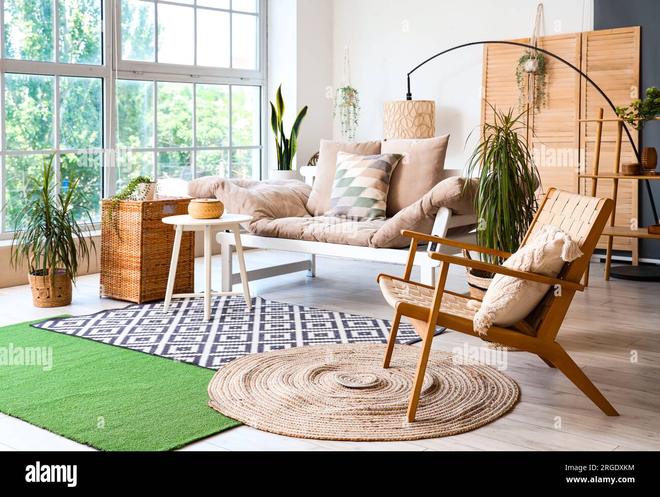 Interior of light living room with cozy sofa, armchair and houseplants ...