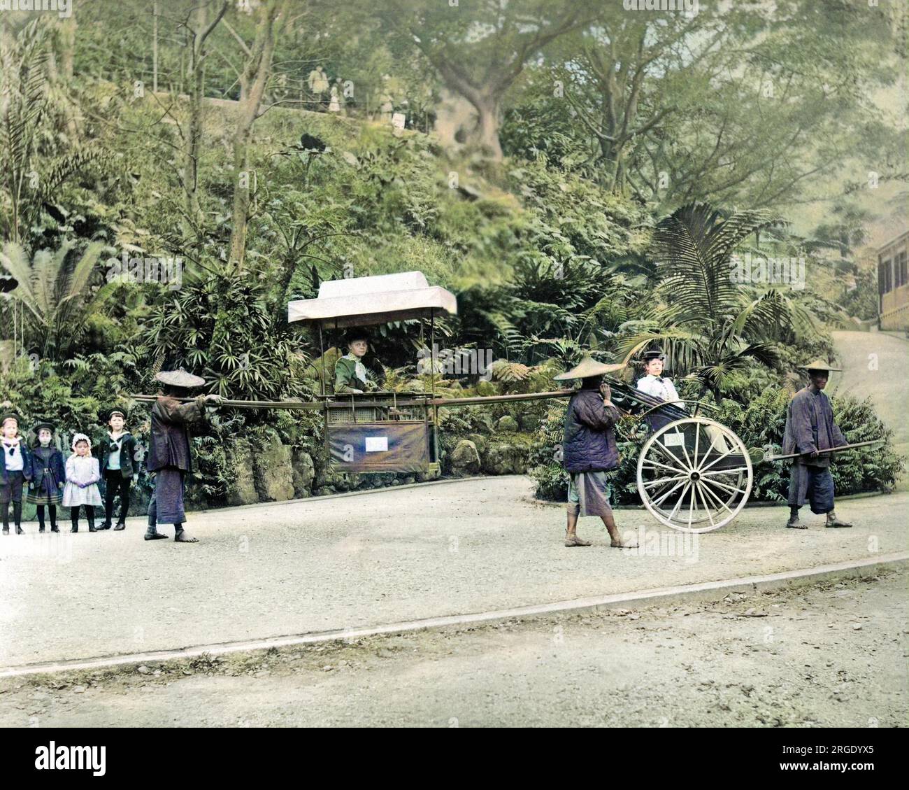 Western woman in carrying chair, Hong Kong, China.  Another Western woman sits in a rickshaw (right), and four Western children stand watching (left). Stock Photo