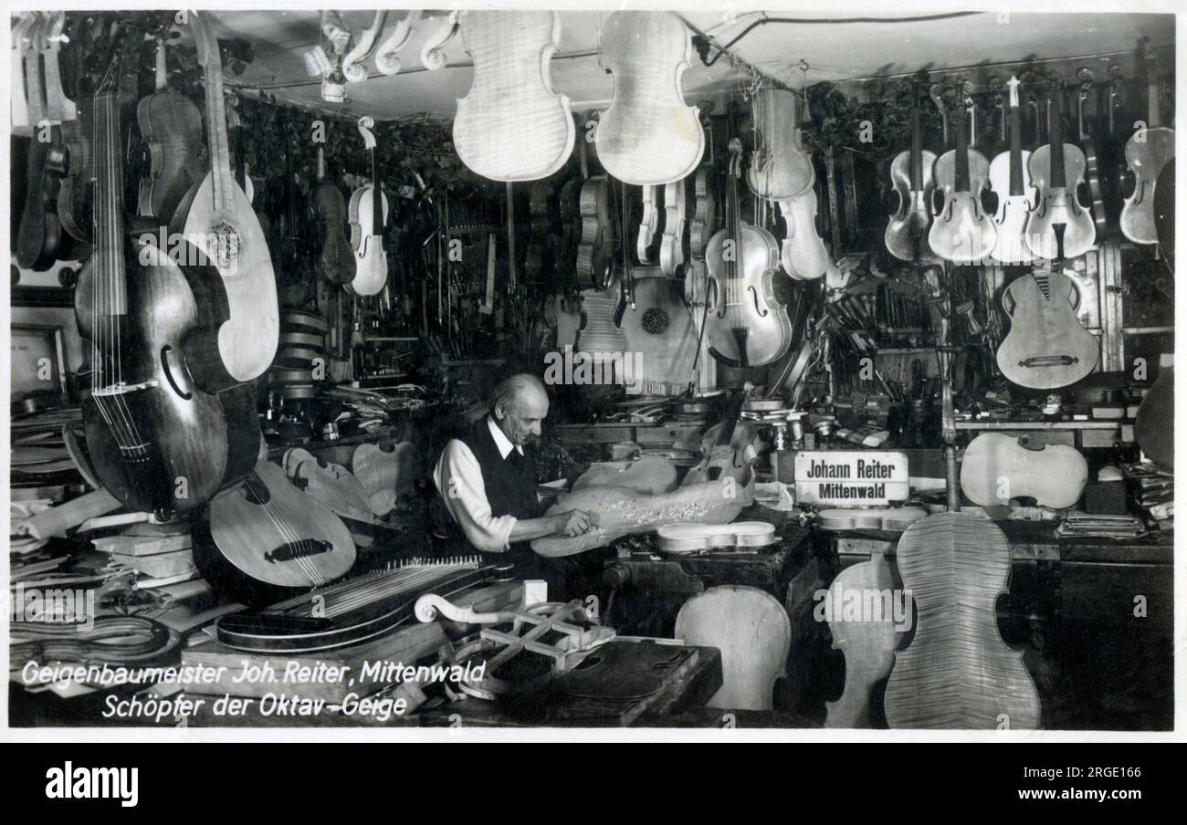Musical instrument maker Johann Reiter of Mittenwald, Germany, surrounded by his wonderful creations, from lutes and cellos to violas and violins. A testament to the high art of carpentry and precision workmanship. The Reiter family have been involved in instrument making in Mittenwald, Germany for well over 100 years. The workshop was founded by Johann Baptiste Reiter (1834-1899), who studied violin-making with Johann Baader and Jean Vauchel, and won several medals and awards for violin-making. He was the leading violin maker in Mittenwald, where out of the total population of 1,800 -- a full Stock Photo