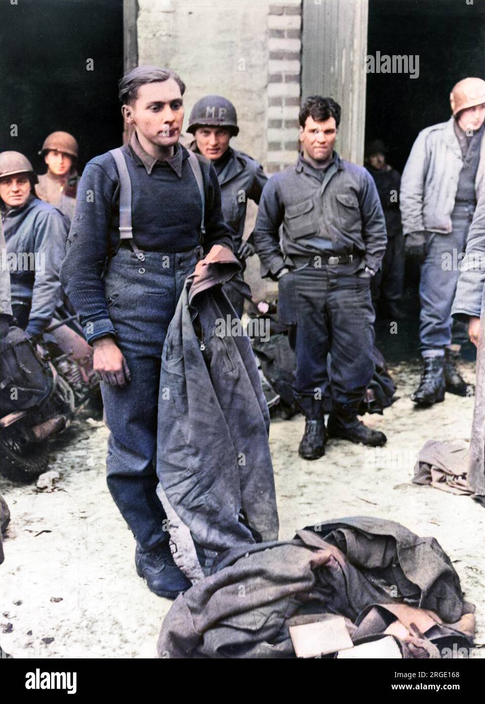 A captured German soldier during the Ardennes counter-offensive is shown holding a pair of American army trousers. He may have been a member of the S.S. unit commanded by Otto Skorzeny, whose men were instructed to wear captured Allied uniforms and carry out actions behind Allied lines in order to create confusion. Stock Photo