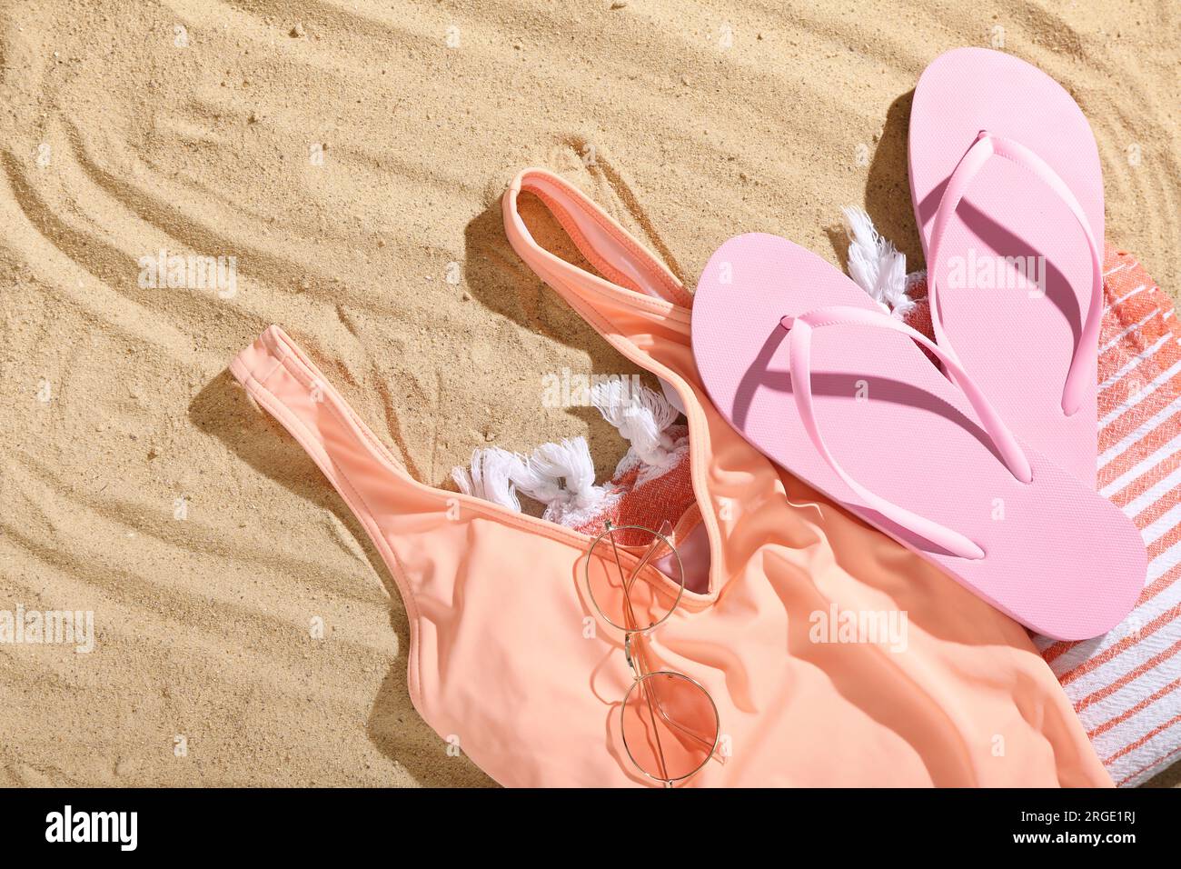 Pair of pink flip flops with swimsuit, sunglasses and blanket on sandy ...