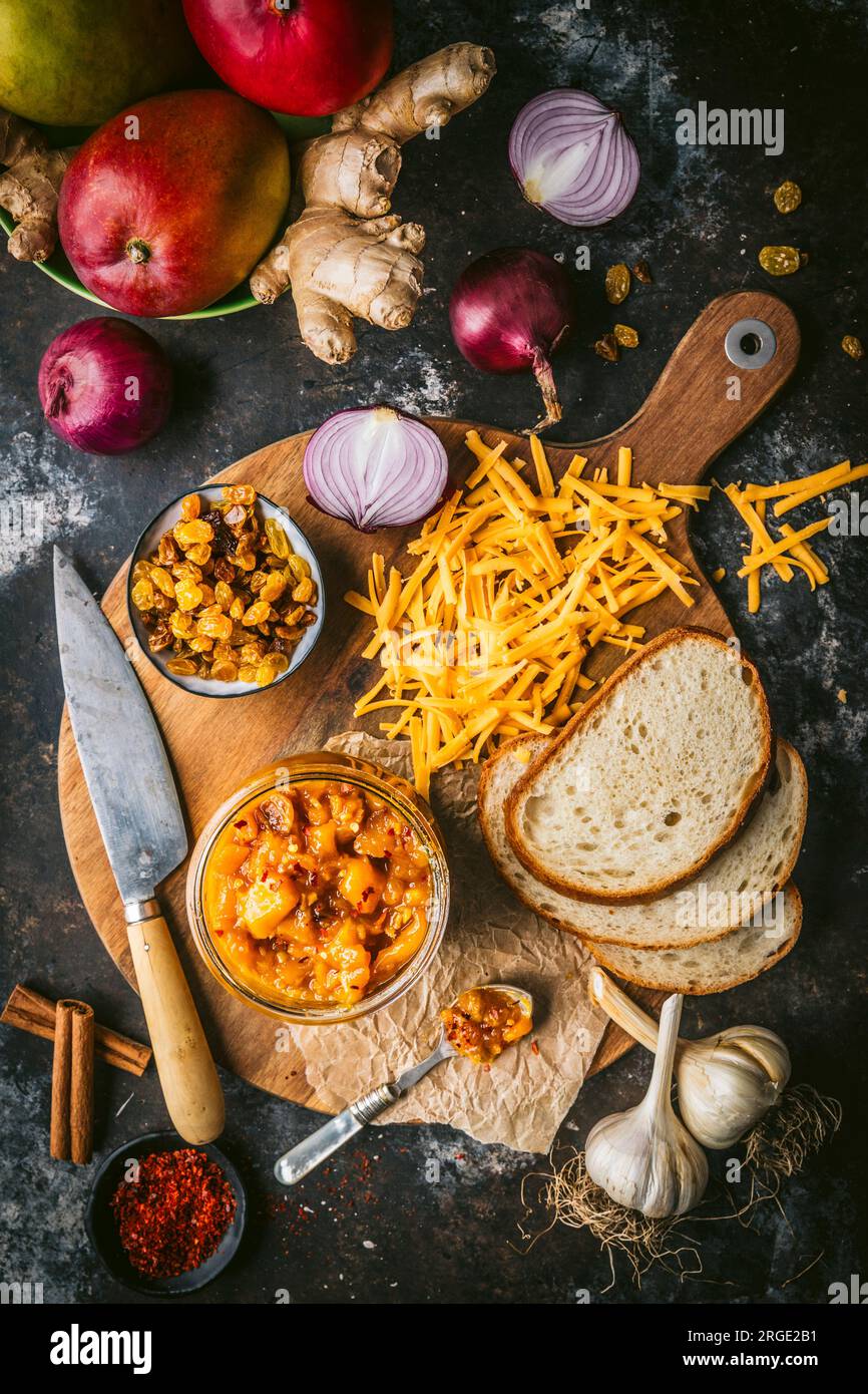 Rustic board with grated cheese, bread mango chutney and sultanas Stock Photo