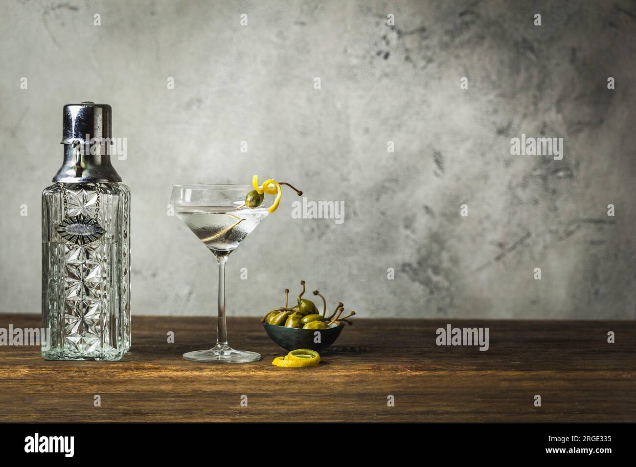 Martini with lemon twist and caperberry, vintage decanter, caperberries in small bowl Stock