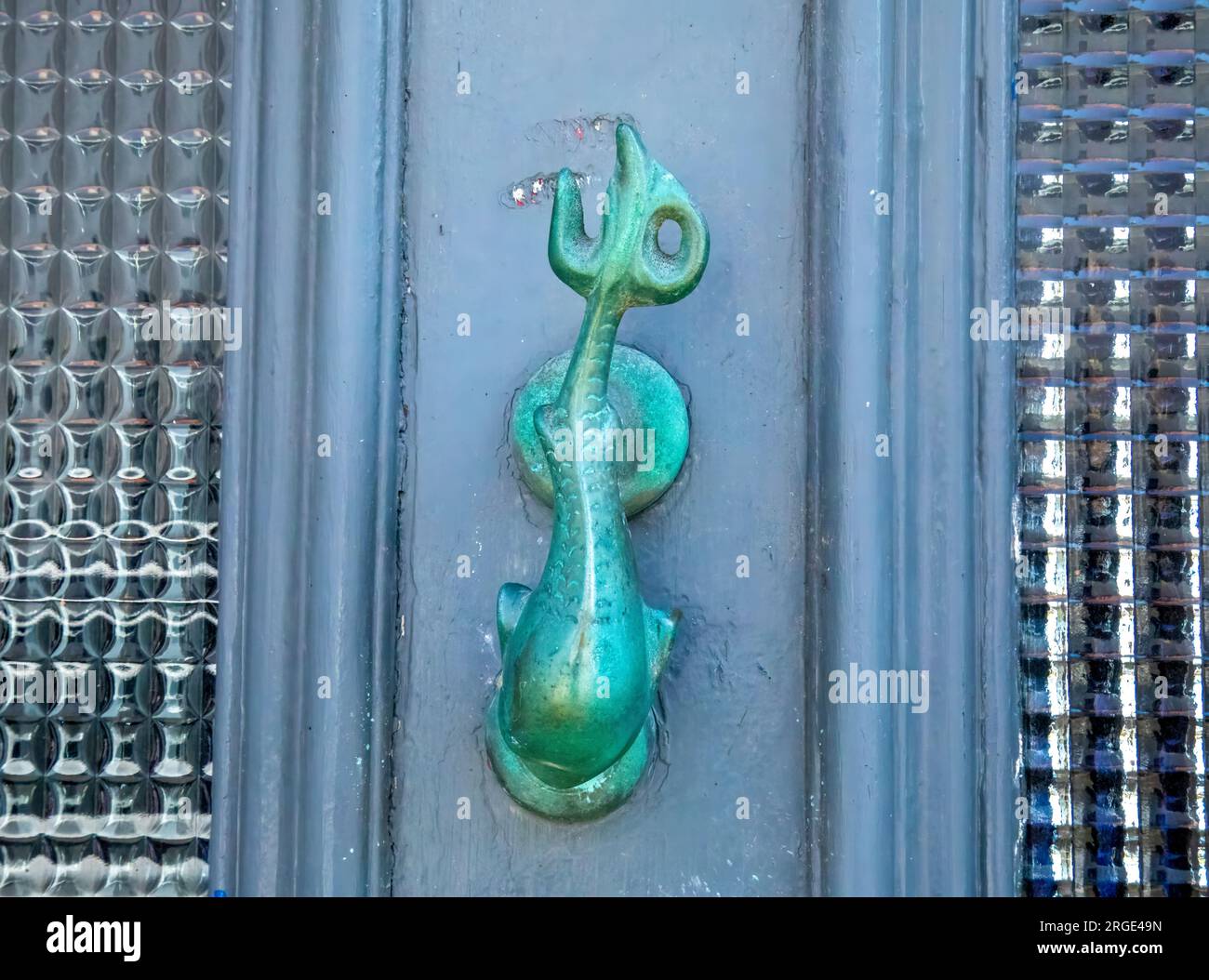 Brass door knocker depicting a nautical theme of a dolphin on a front door in a coastal town Stock Photo