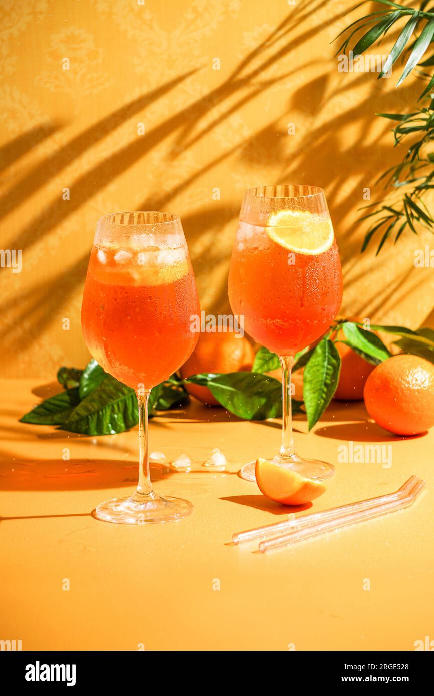 aperol spritz cocktail with ice, a misted refreshing drink, on an orange background, sunlight, shadows, a summer drink in a wine glass Stock Photo