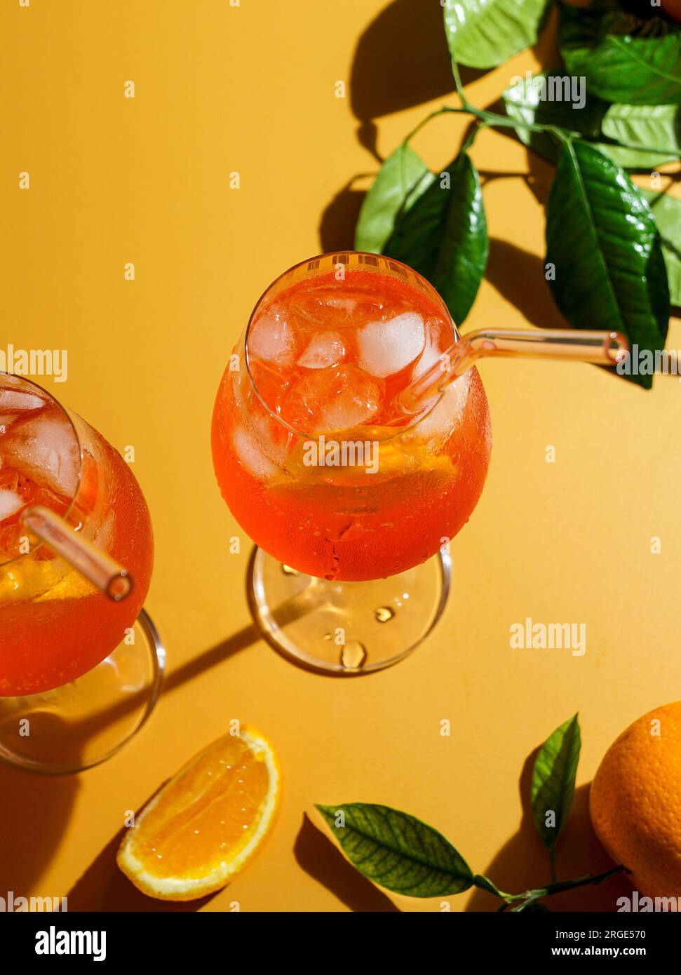 aperol spritz cocktail with ice, a misted refreshing drink, on an orange background, sunlight, shadows, a summer drink in a wine glass Stock Photo